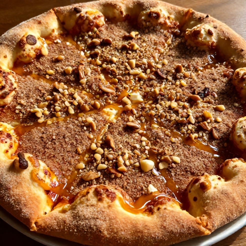 Plated cinnamon sugar pizza. Topped with chopped nuts and a drizzle of honey.